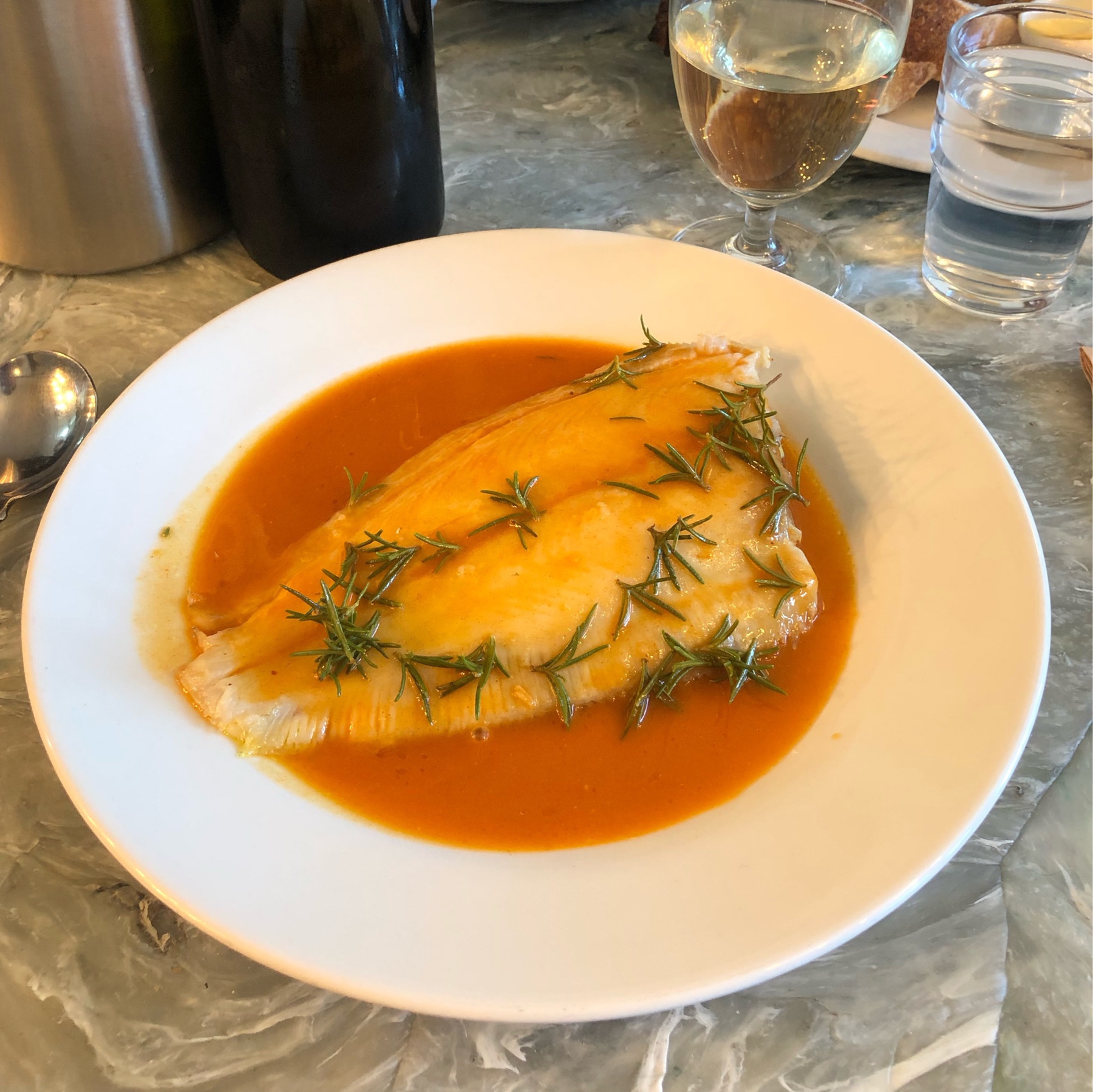 Sea bream on a paprika butter with rosemary on top in a white plate