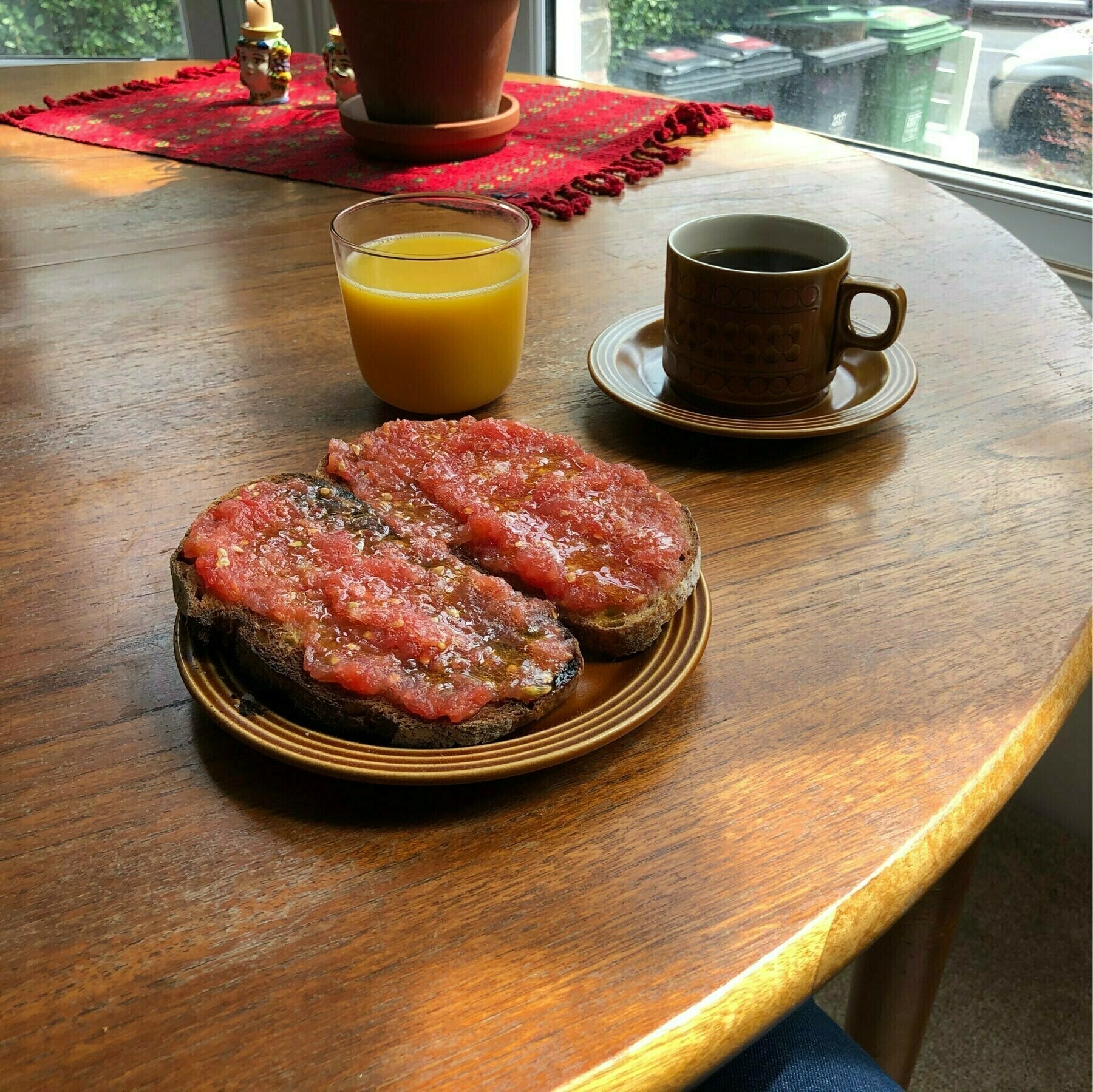 Toast with tomato, coffee and orange juice on a brown wood table