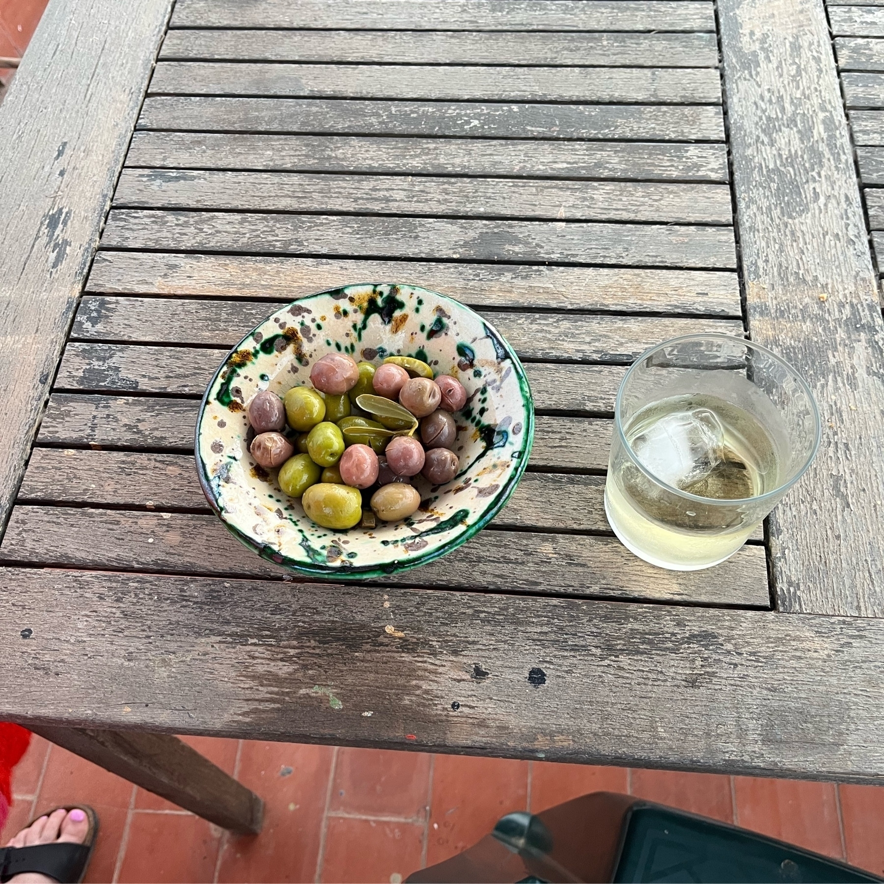 Green and black olives on a bowl next to a glass of fino.